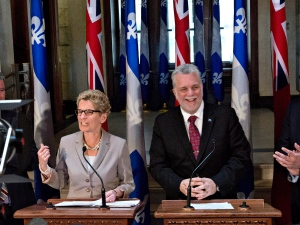 Ontario Premier Kathleen Wynne, left, speaks at a news conference following a meeting with Quebec Premier Philippe Couillard, right, Monday at Couillard's office in Quebec City. (The Canadian Press)