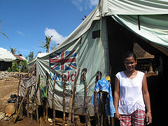 A woman stands in front of a tent provided by UK aid in the Philippines. Photo: DFID