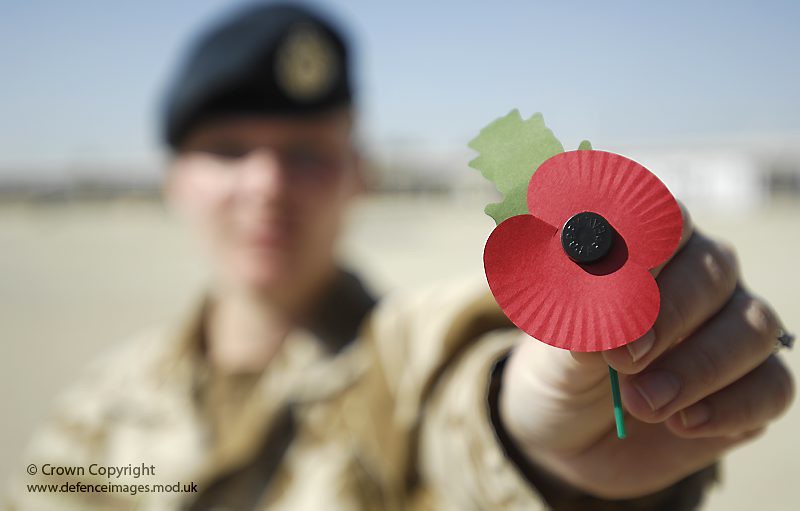 A soldier holds out a poppy whilst on service in Afghanistan.