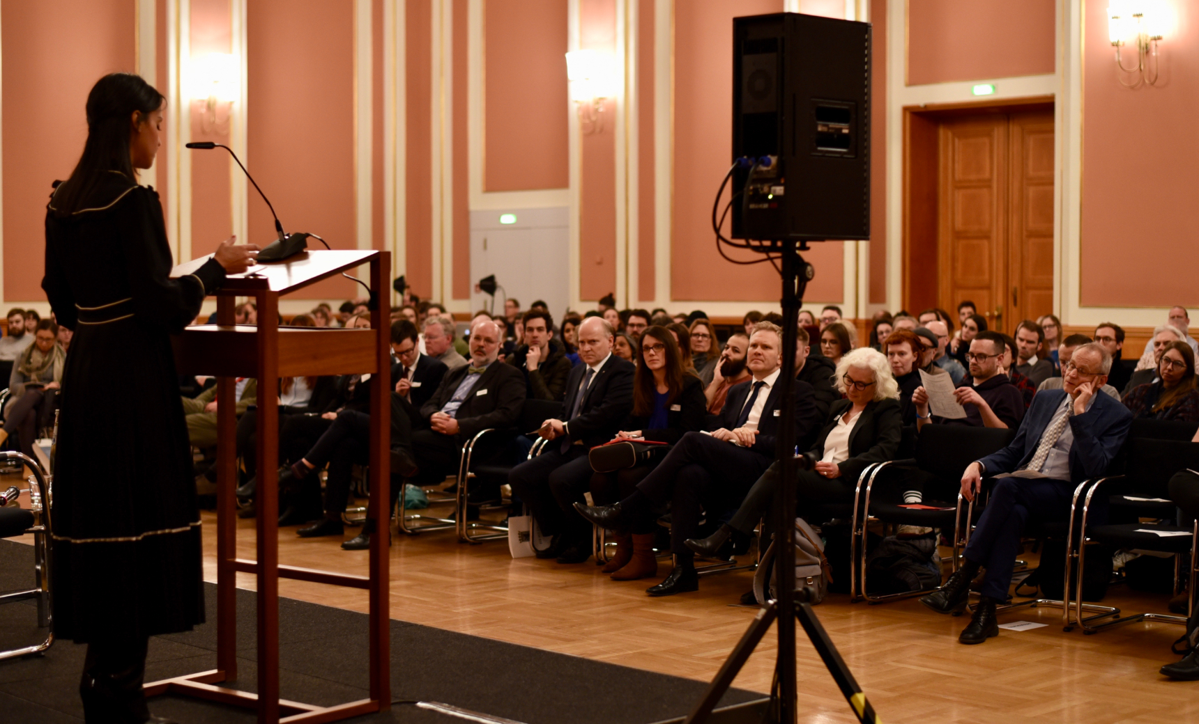 A woman speaking to a large group of people.