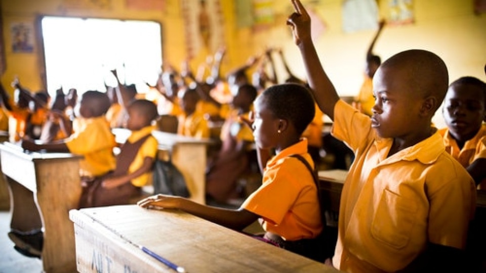 Students in a classroom in Ghana. Some have their hands up