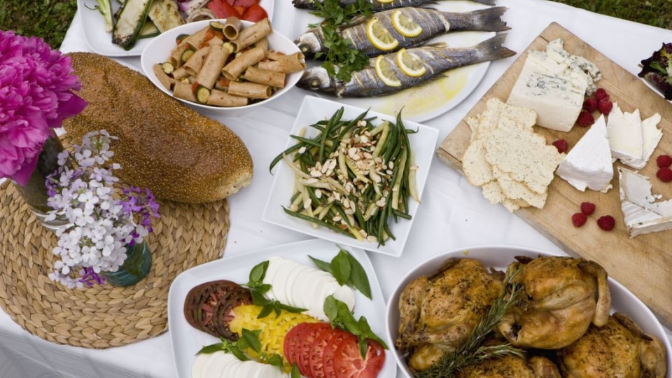 Fish, grilled vegetables and bread on a table with flowers