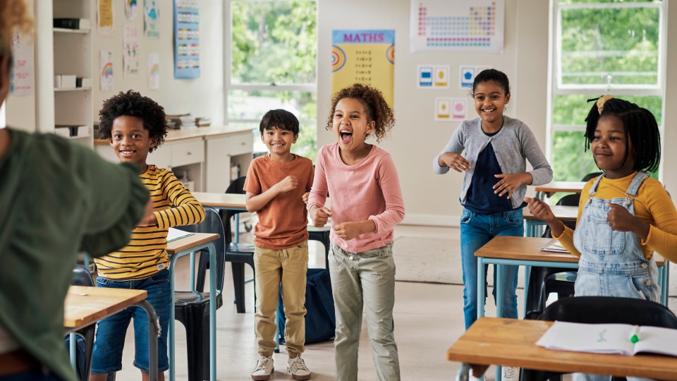 diverse group of primary children standing up in classroom