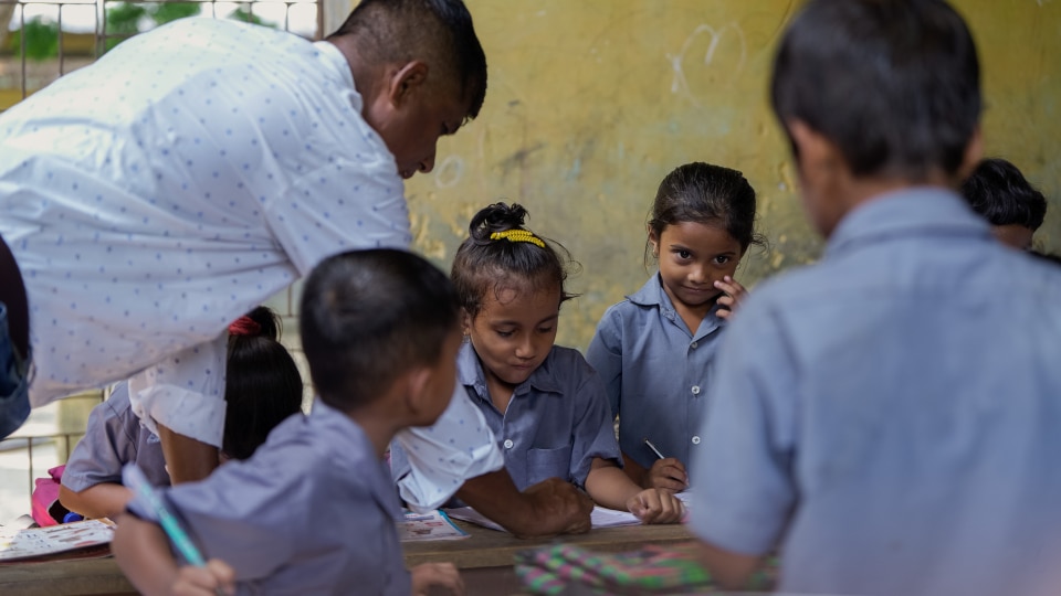 South Asian teacher in a classroom with his primary learners