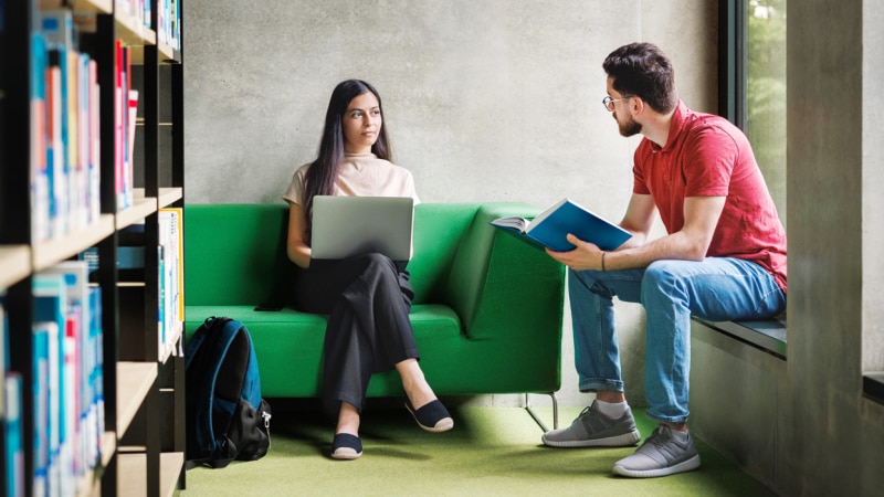 Two post graduate students discuss in the library