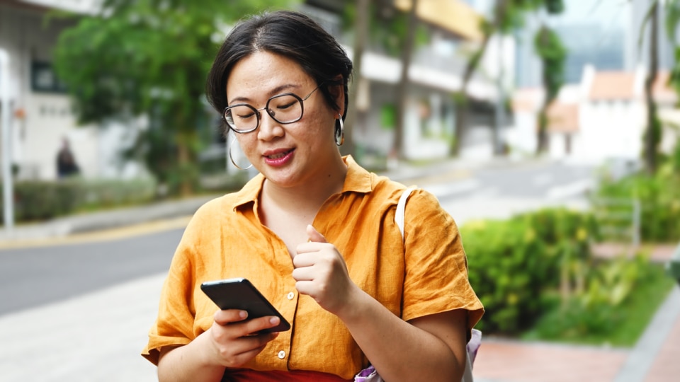 A woman checks her phone, walking down the street