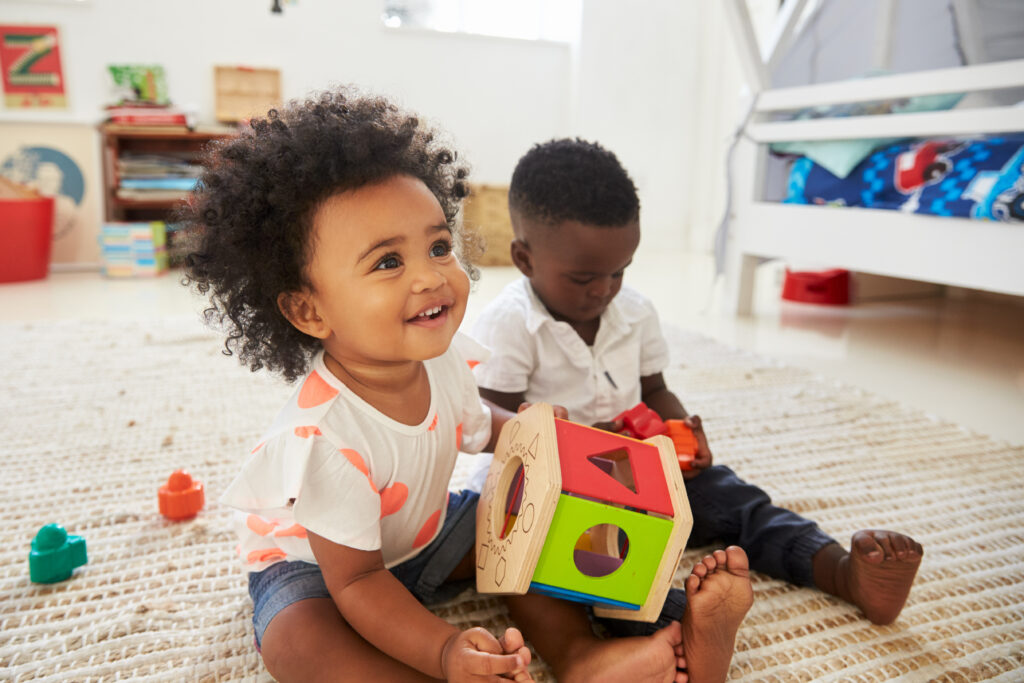 Little girl and boy sitting on the floor playing with toys