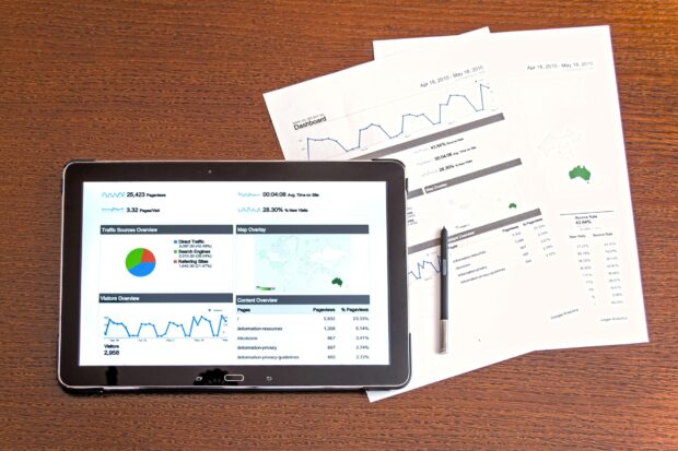 Tablet screen with a number of graphs displayed placed on top of papers