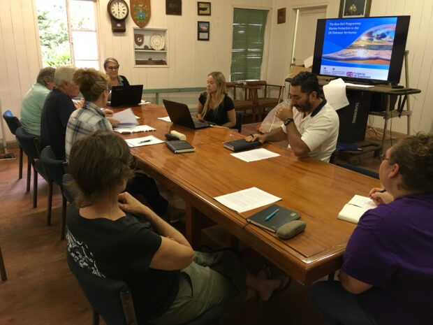 Dr Emily Hardman and members of the Pitcairn Island Council sitting around a table with laptop computers and notepads.
