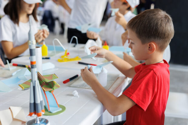 An image of children making aeroplanes with glue and other materials