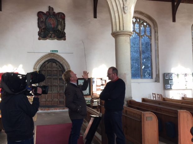 A BBC camera films a presenter looking up into a church for bats with a Natural England expert