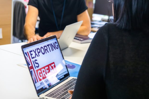 A woman is using a laptop, which displays the message "Exporting is great"