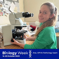 Image of a female scientist sat next to a microscope