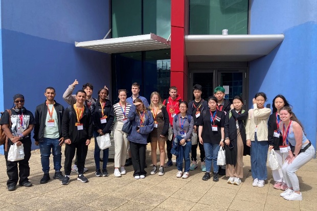 Large group image outside a blue coloured building