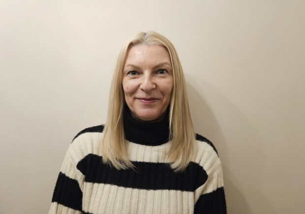 A head and shoulders picture of Jane Davies, who is smiling. Jane is wearing a black and cream striped jumper.