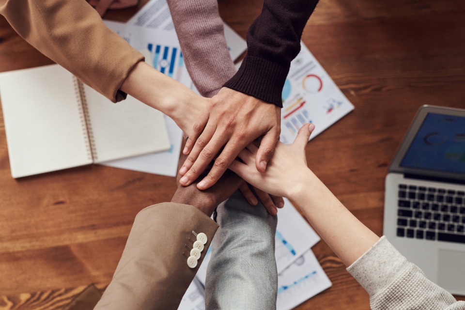 multiple people placing their hands on top of each other in a circle