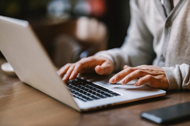 Image shows hands typing on laptop.
