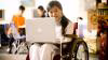 Wheelchair user smiling at her laptop