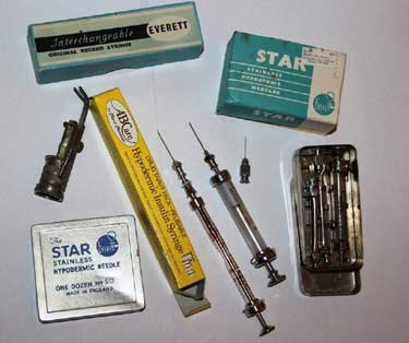 Various equipment used to treat diabetes over the past couple of decades. Top left includes old syringe boxes, metal syringes in a metal case and packaging.