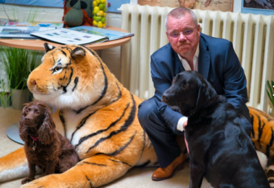 Pete, Headteacher, knelt on the floor with two dogs and a stuffed animal toy