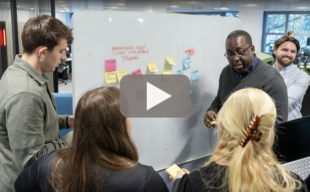 a team having a standup with a 'play' button in the middle