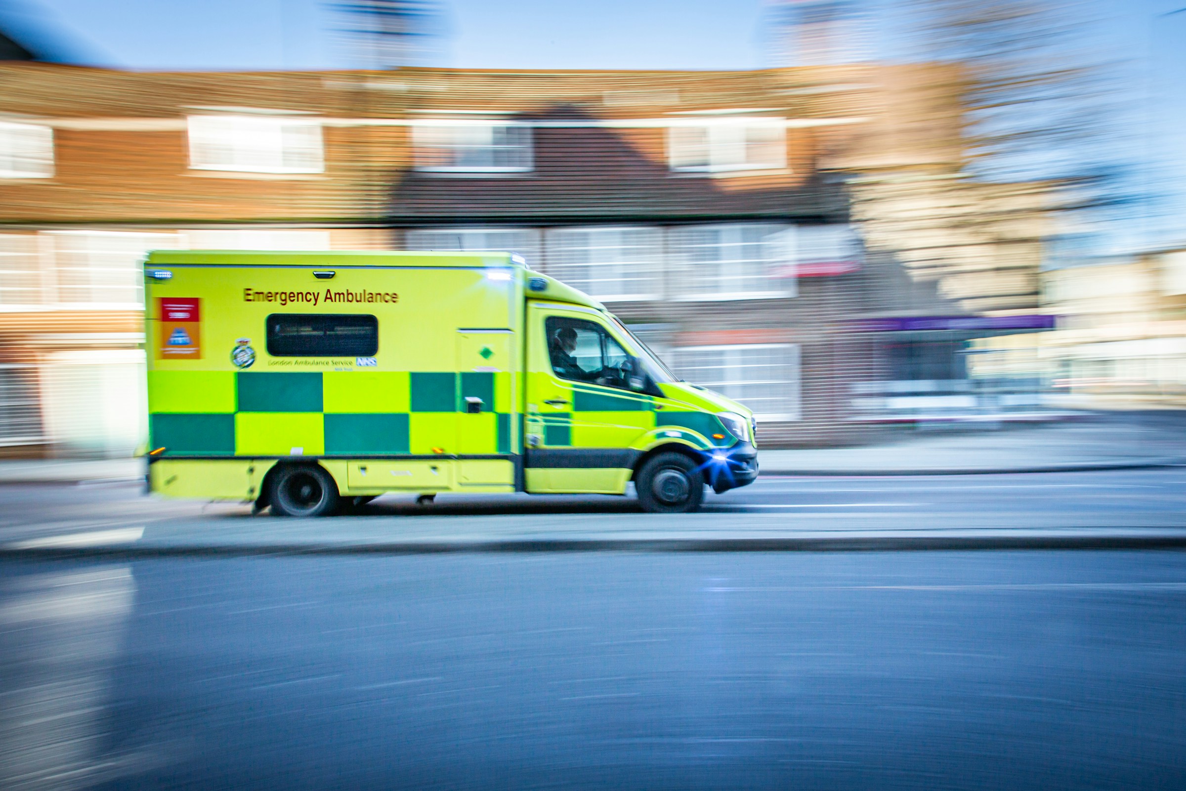 Ambulance pictured against a blurred background of houses.