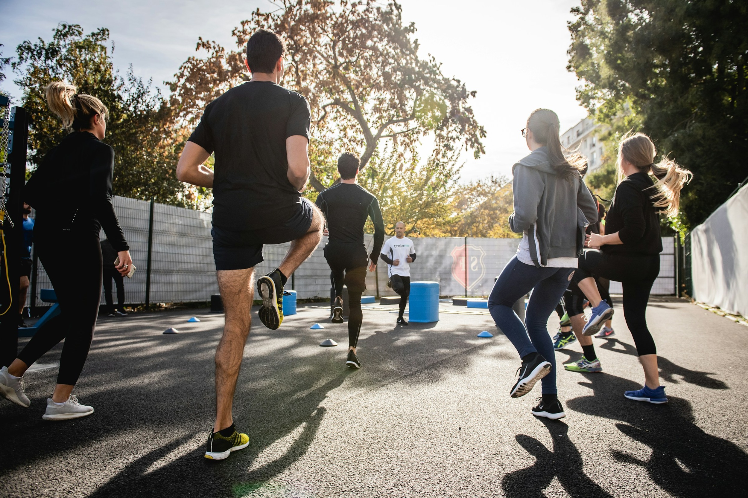Five people in gym clothes taking part in an exercise class outdoors near some trees. Credit: Gabin Vallet, Unsplash.