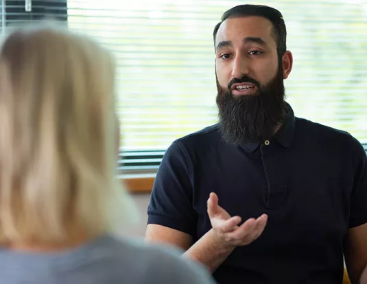 British Asian man talks to female colleague in office
