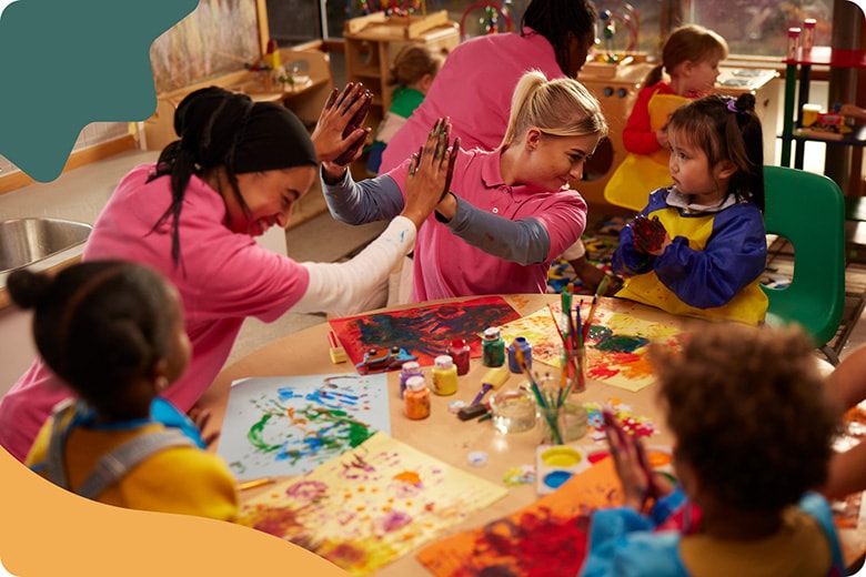 Adults cheer children to paint in the classroom.