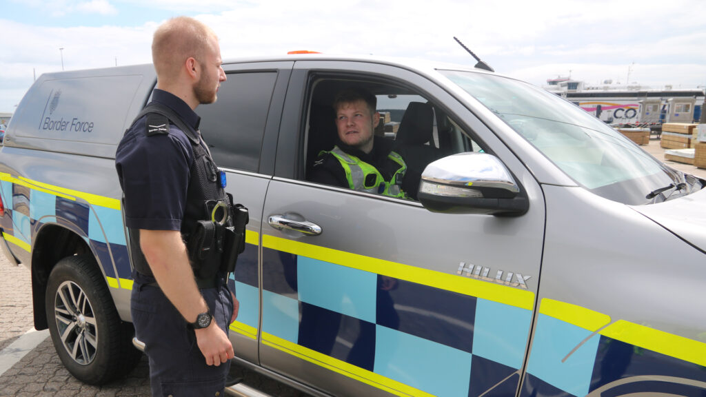 two Border Force Officers. One in a vehicle and one standing