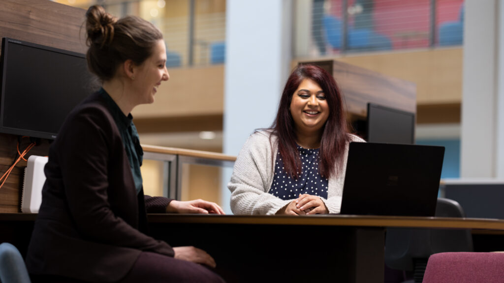 two members of staff, seated looking at a laptop