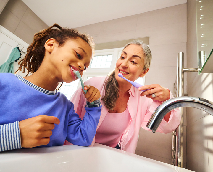 Photo of a girl and woman brushing their teeth