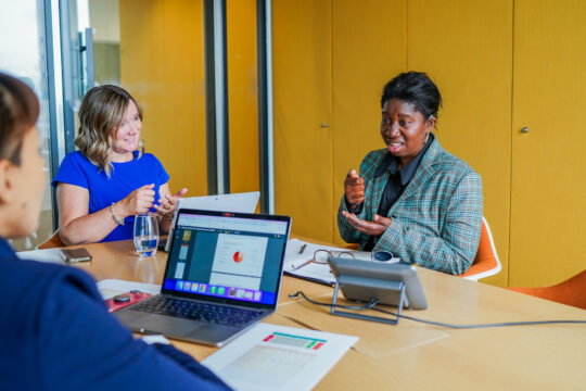 Three (3) women in a meeting who are using sign language.