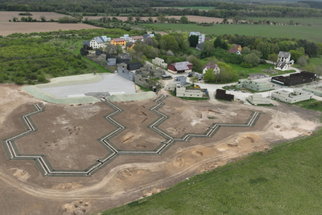 Aerial view of a new trench system, with buildings to the right.
