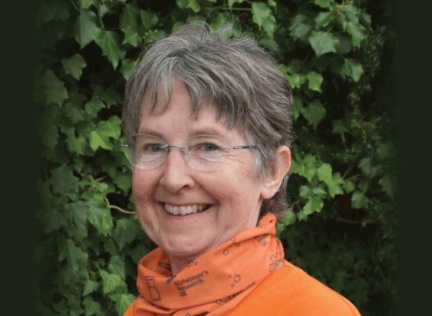 Image of Jill smiling in front of a green hedge.