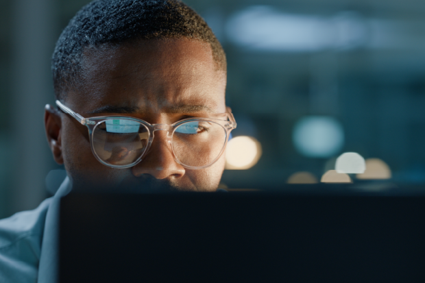 A man wearing glasses is looking at a computer screen.