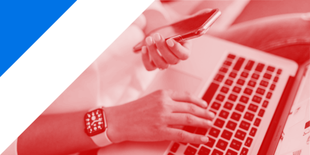 A person holding a phone in their hand and also using a laptop